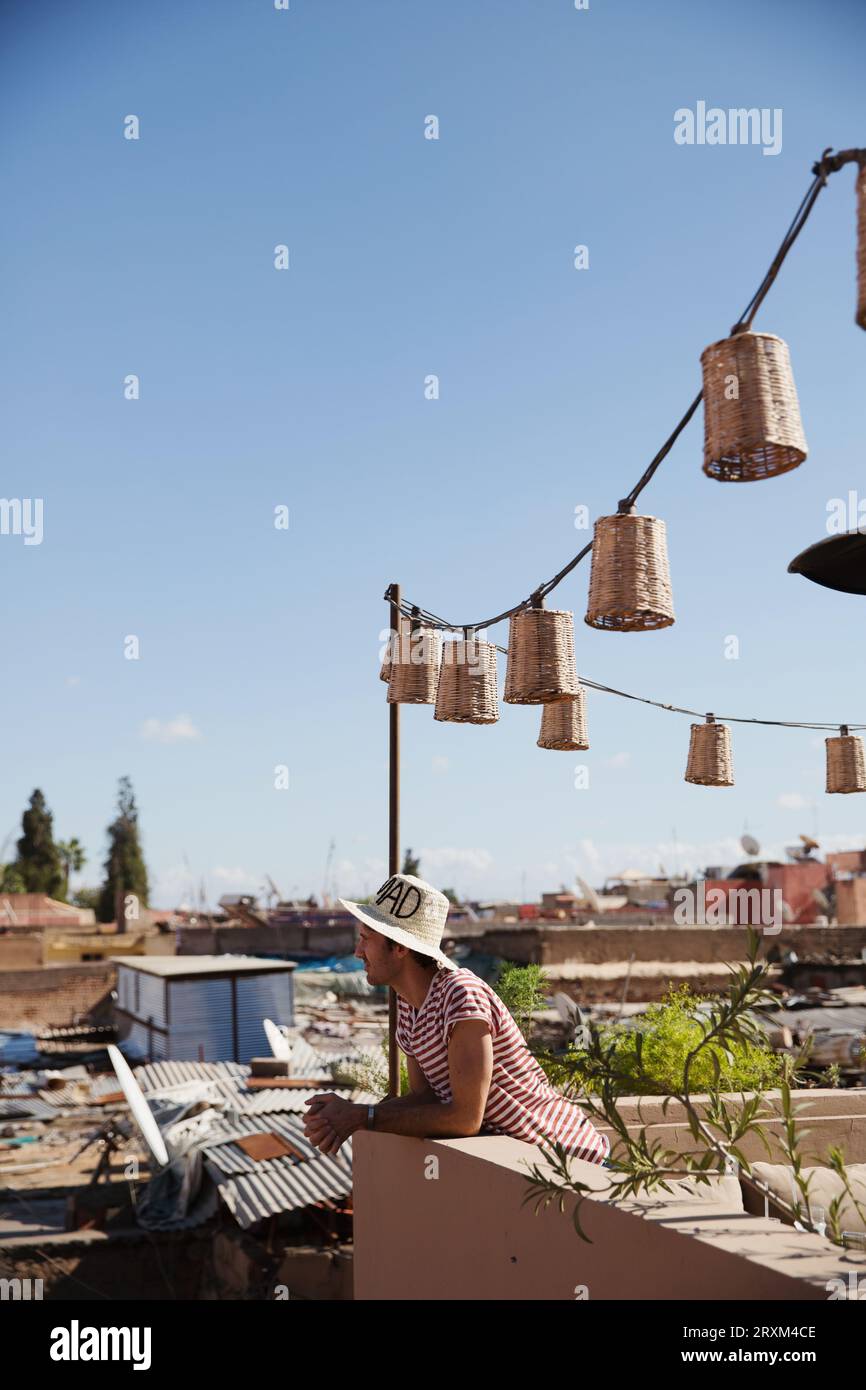 Man wearing straw hat on rooftop with lanterns Stock Photo
