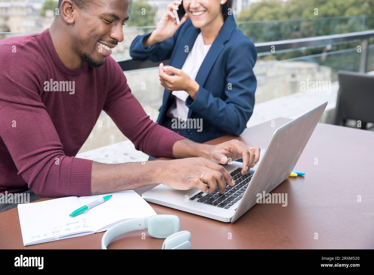 Smiling young man using laptop on balcony Stock Photo