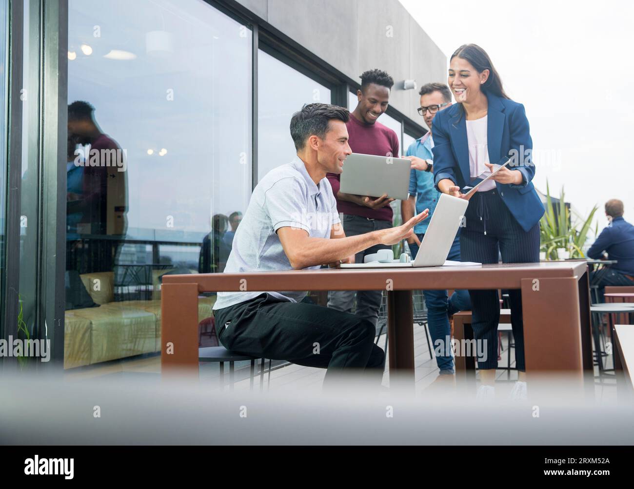 Colleagues using laptops on balcony Stock Photo