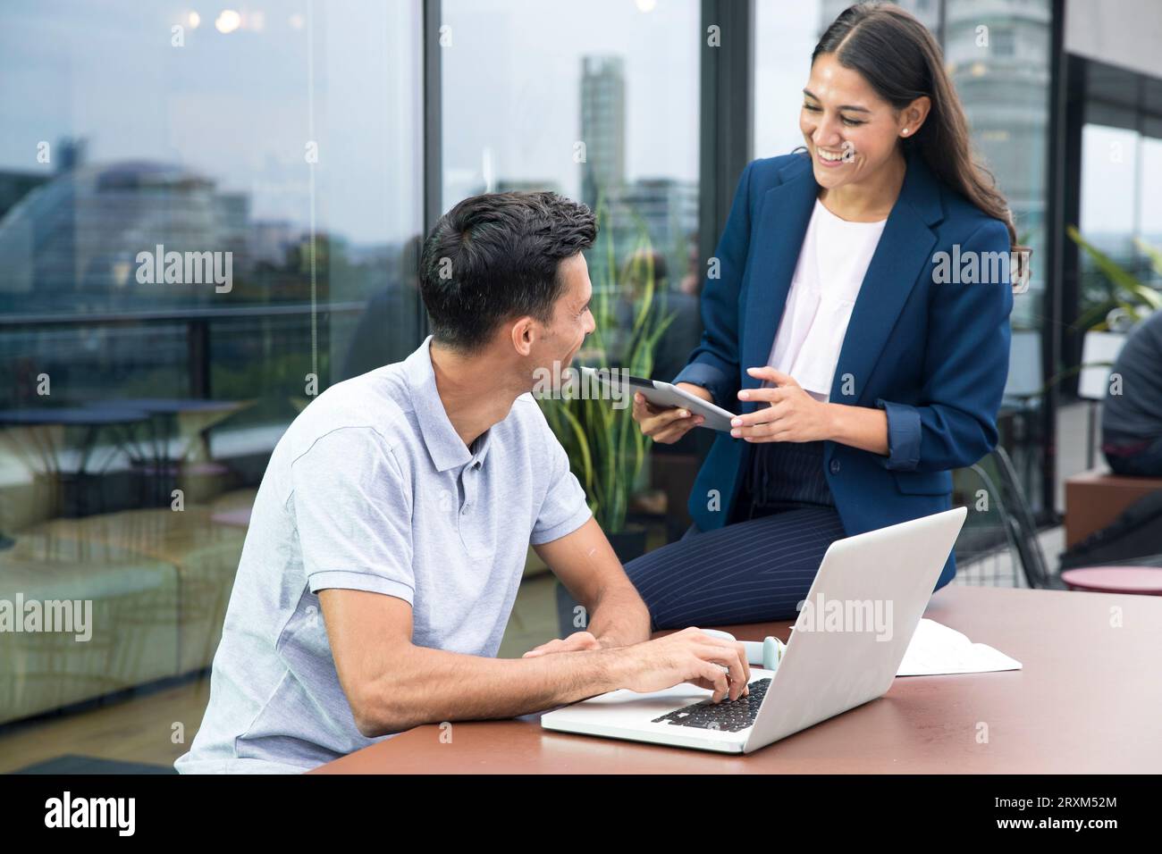 Colleagues using laptop and digital tablet on balcony Stock Photo