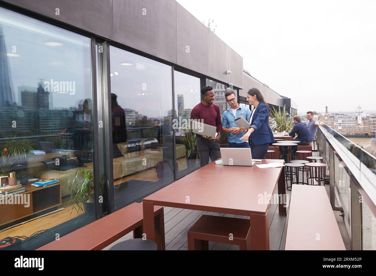 Colleagues using laptops on balcony Stock Photo