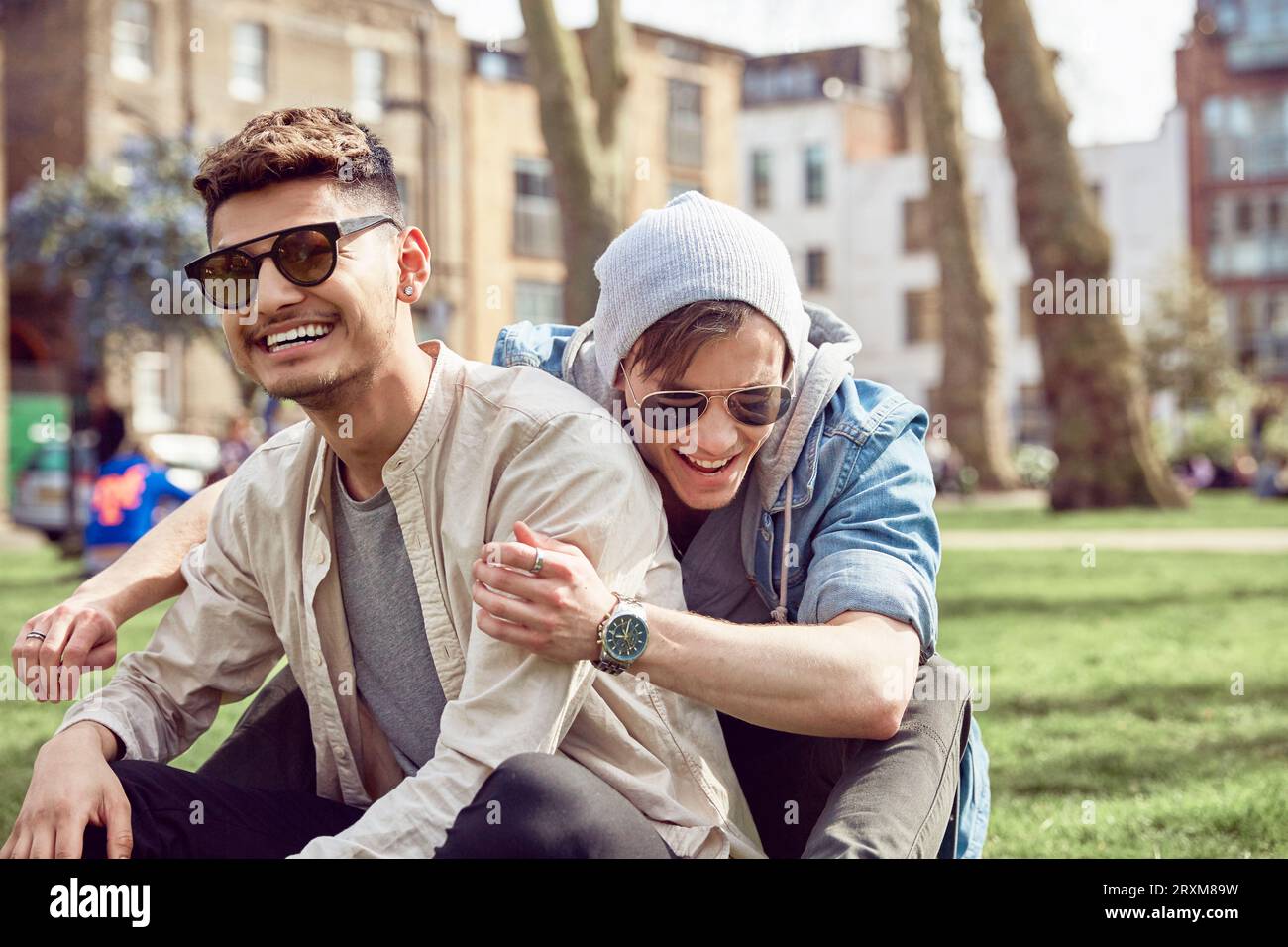 Gay teenage couple sitting together in park Stock Photo
