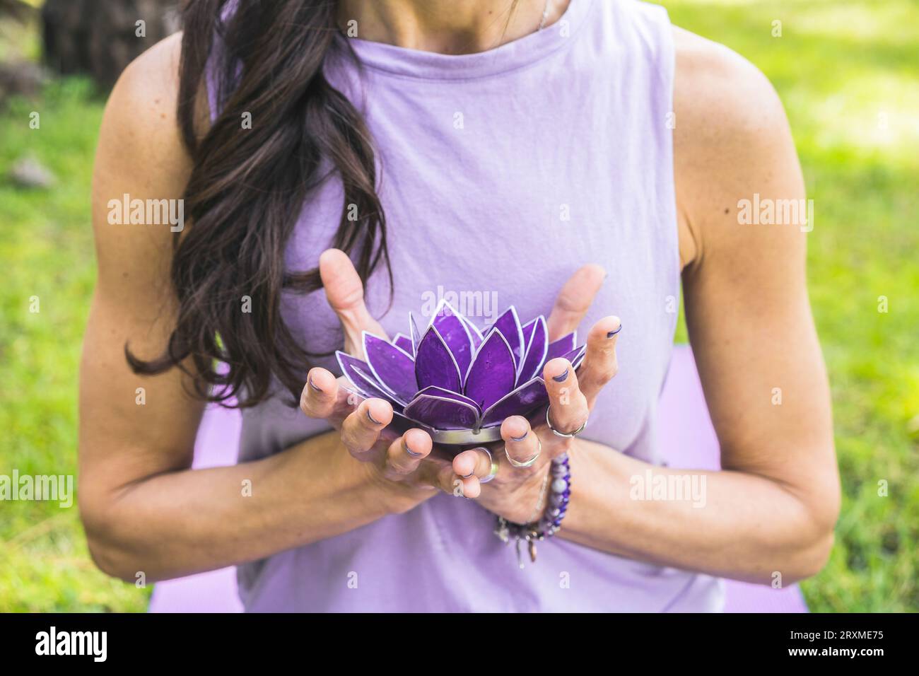 Close up of woman's hands holding a purple glass lotus. Yoga and meditation concept. Stock Photo