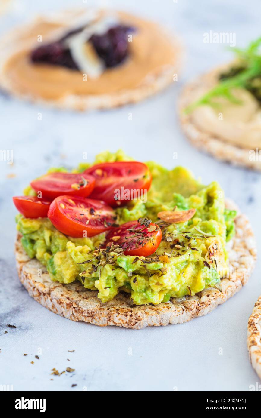 Healthy crispbread toasts with avocado, peanut butter and hummus. Vegan breakfast concept. Stock Photo