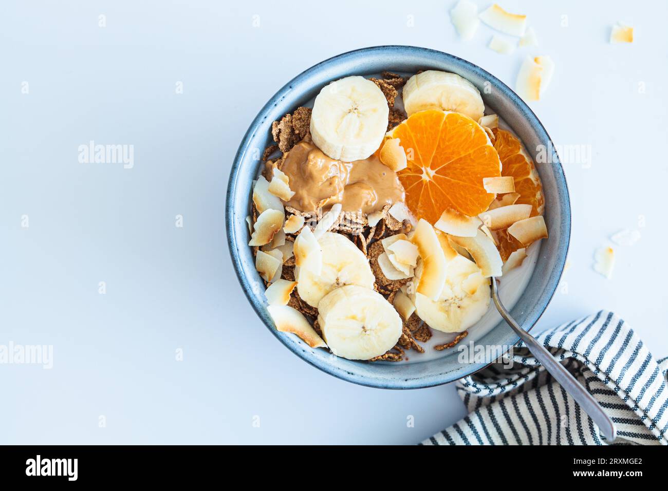 Winter wholewheat breakfast cereals with tangerine, coconut chips, peanut butter and banana, top view. Vegan breakfast concept. Stock Photo