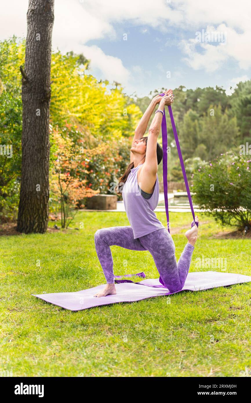 Mid adult female exercising yoga with strap. Stock Photo