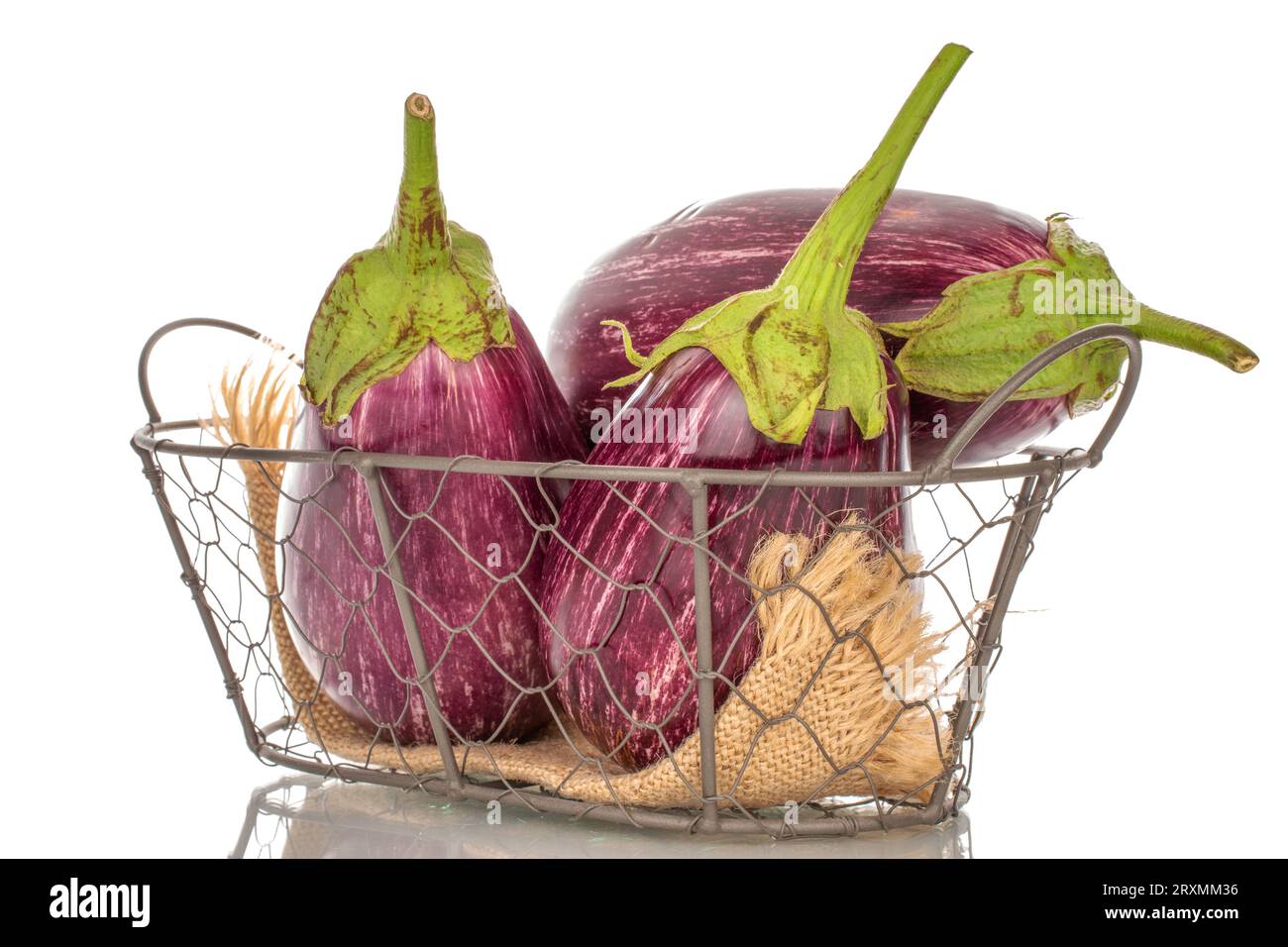 Three organic ripe eggplants in a basket, macro, isolated on white background. Stock Photo