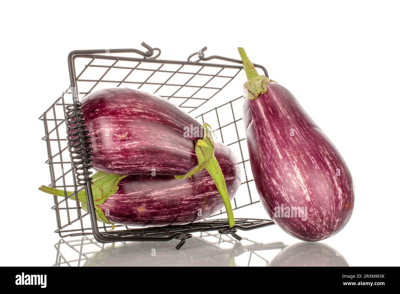 Three organic ripe eggplants in a basket, macro, isolated on white background. Stock Photo