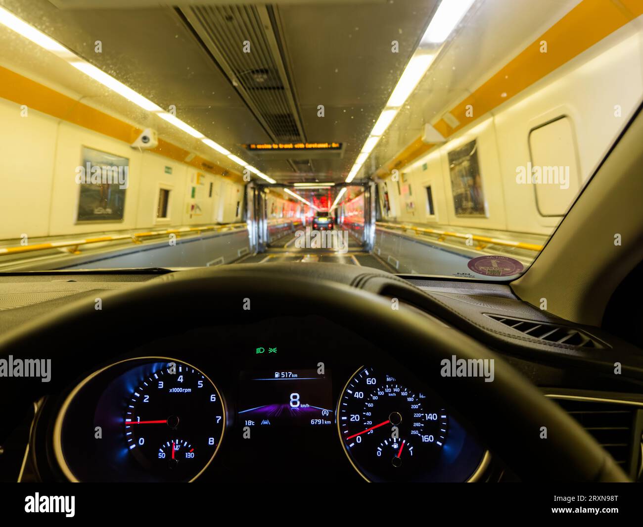 A car drives down inside the Eurotunnel train at night at Coquelles near Calais in France before being transported under the English Channel to Folkes Stock Photo