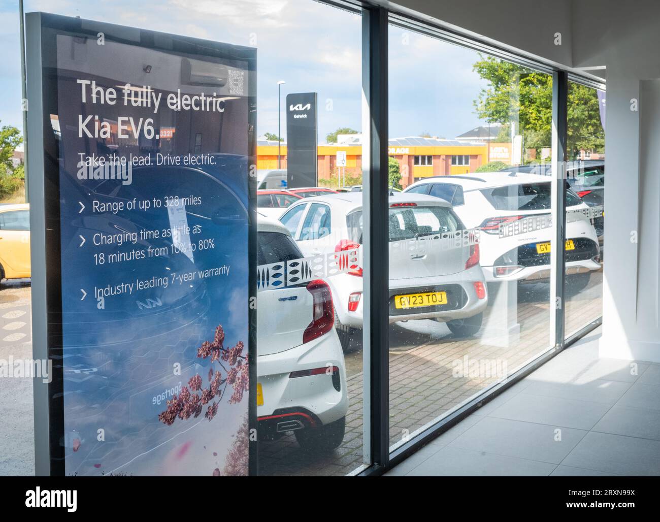 A sign inside a Kia car dealership in Crawley, UK, advertising the fully electric Kia EV6. Outside the windown Kia petrol cars are lined up for sale. Stock Photo