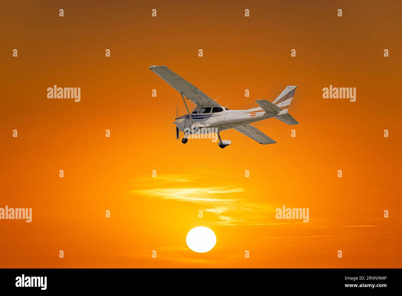 Single engine ultralight airplane flying under an orange sky at sunset Stock Photo