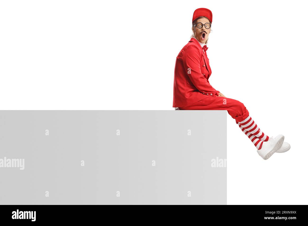 Funny entertainer in a red suit sitting on a wall isolated on white background Stock Photo