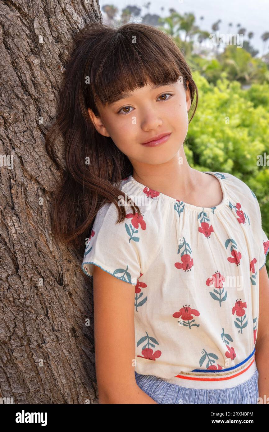 11 year old girl leaning against a tree Stock Photo