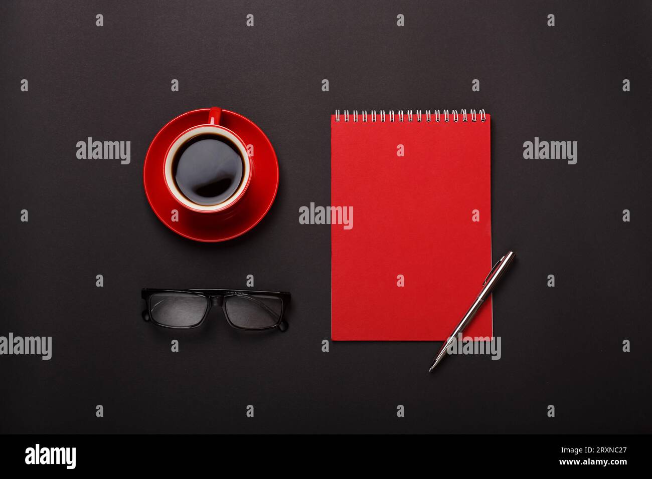 black background red coffee cup notepad pen glasses empty Stock Photo