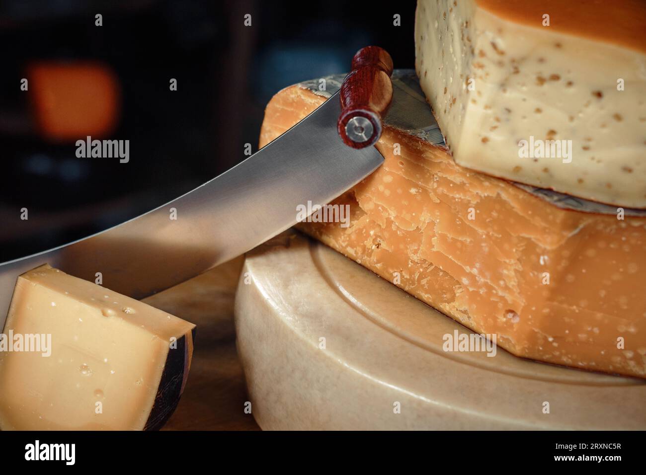 Cheese heads with slices and knives lie on a wooden board with an interior Stock Photo