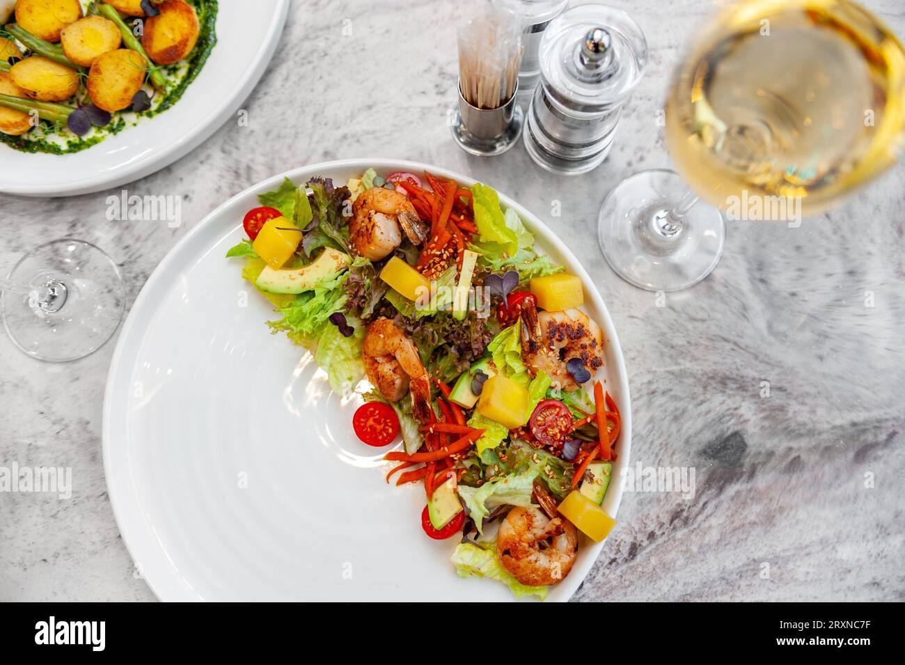 Salad with fried shrimp, mango, avocado and cherry tomatoes on a white plate. High quality photo Stock Photo
