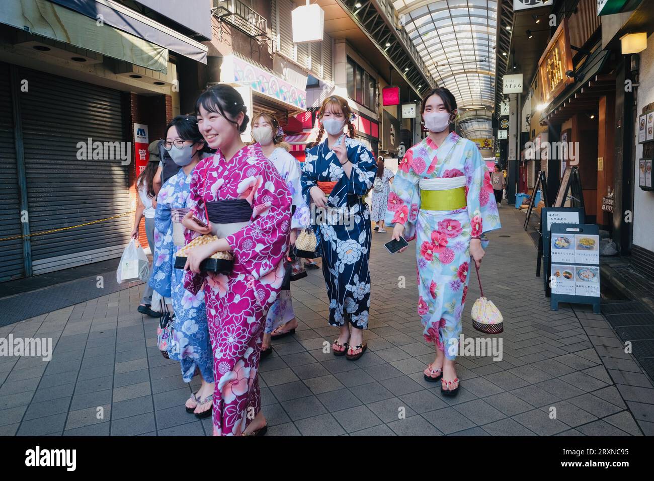 Japanese girls dressed in kimonos walk along a covered arcade in  Asakusa,Tokyo, Japan Stock Photo