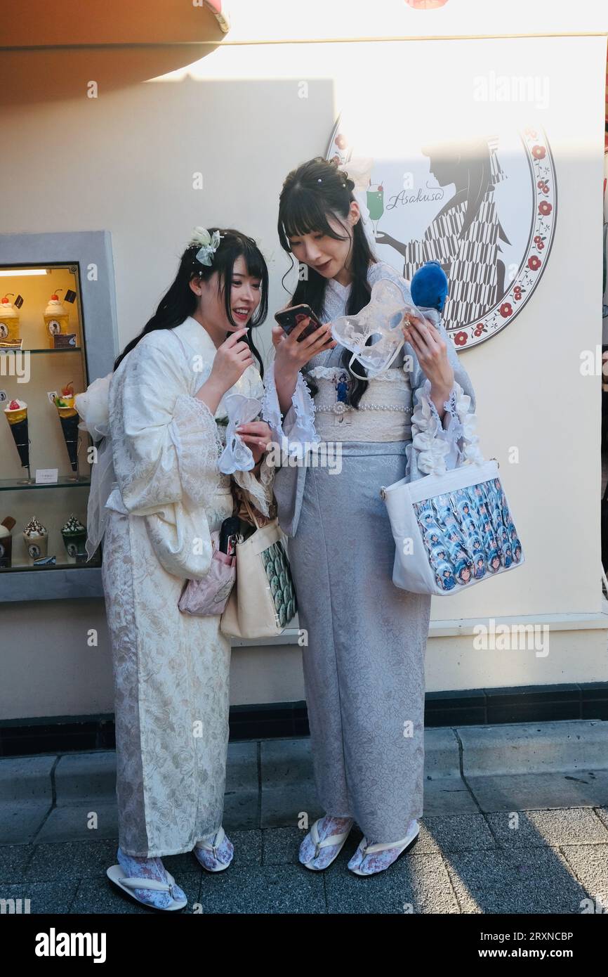 Two Japanese girls dressed in kimonos laugh at photos on a smartphone in  Asakusa,Tokyo, Japan Stock Photo