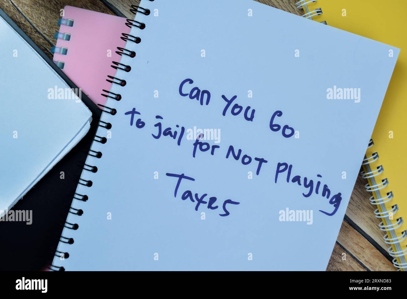 Concept of Can You Go To Jail For Not Playing Taxes write on book isolated on Wooden Table. Stock Photo