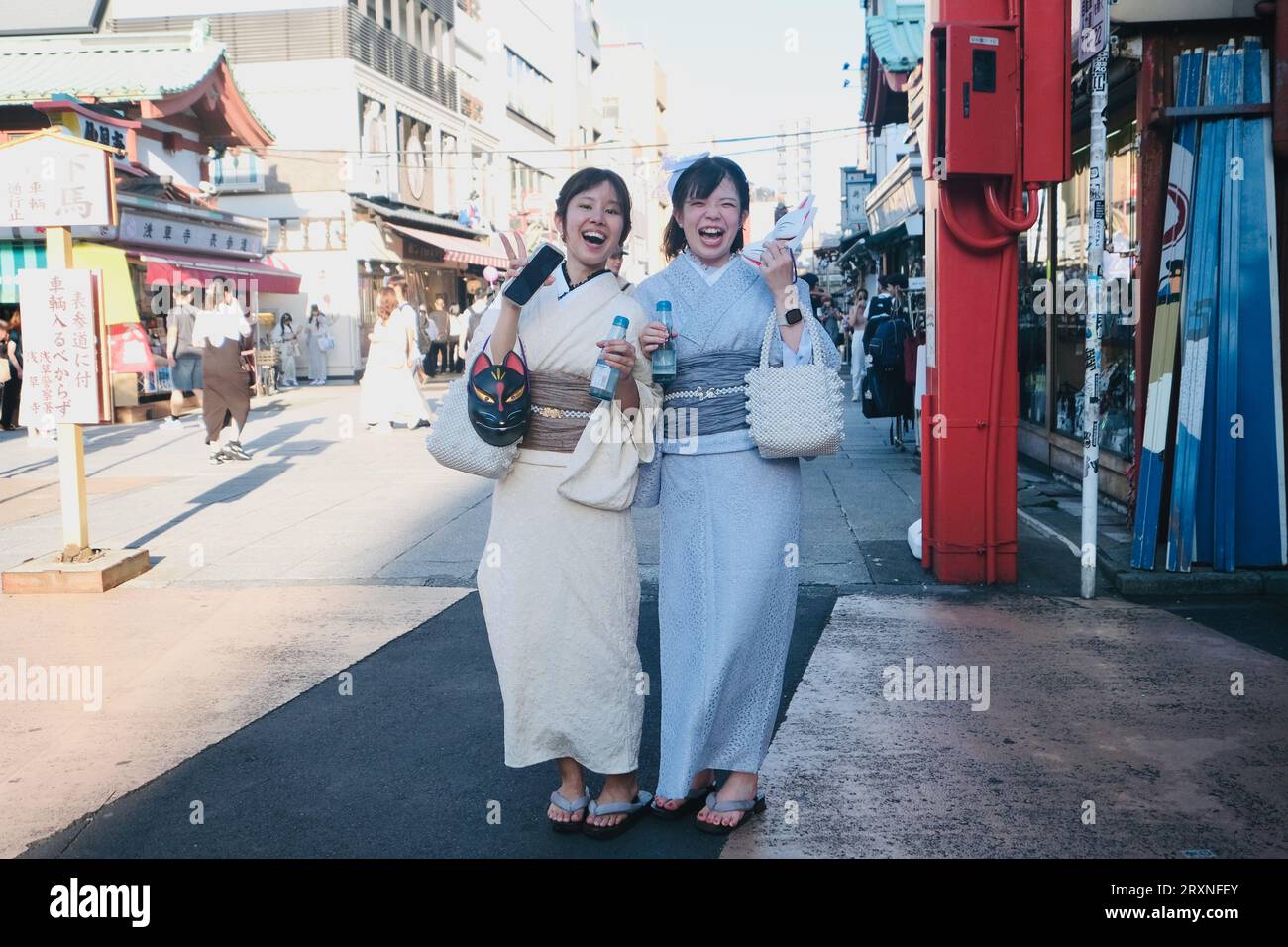 Two Japanese girls dressed in kimonos stand in the road in Asakusa in Tokyo, Japan Stock Photo