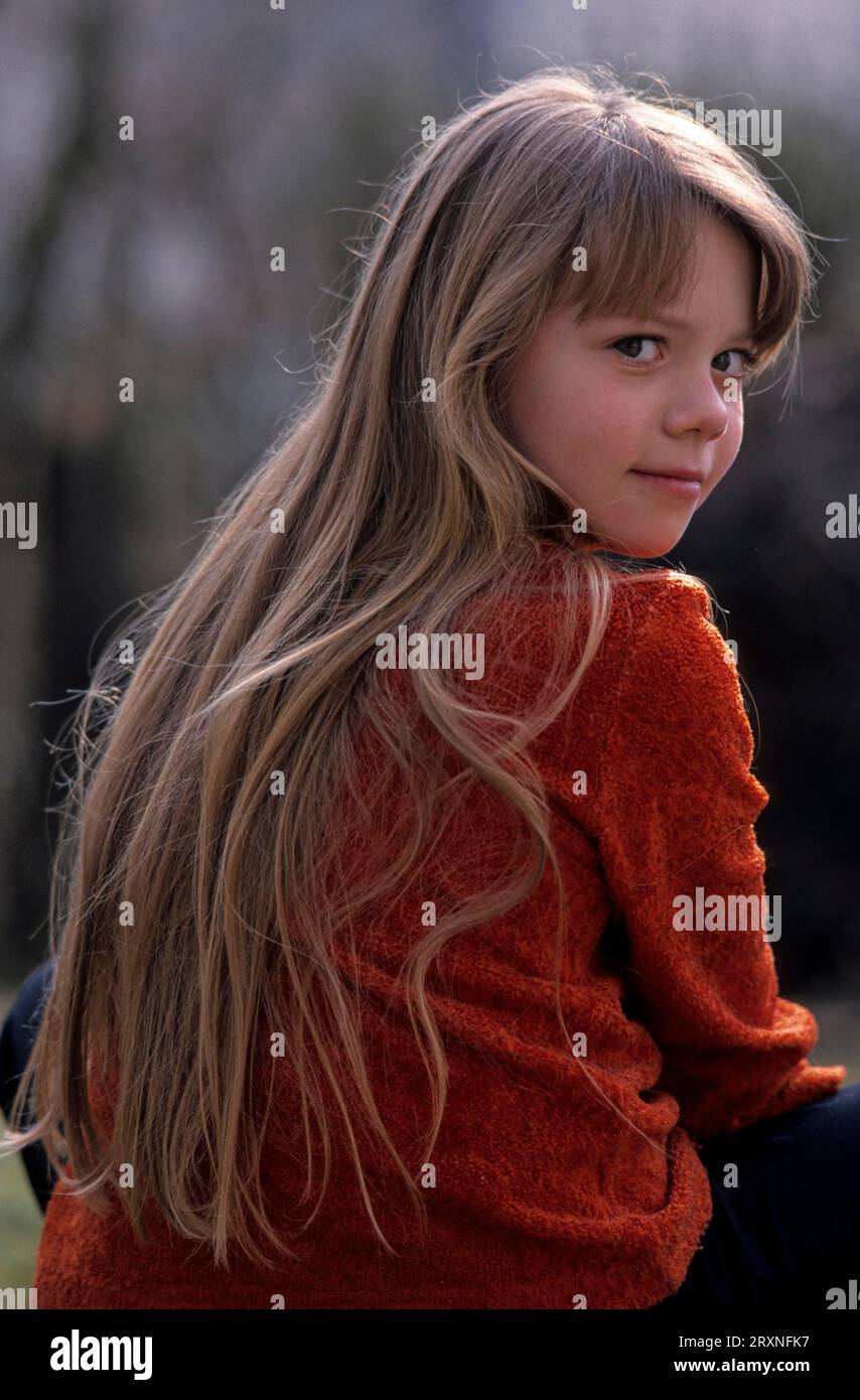 Young little girl, 6, 7, 8 9, 10 years, looking over her shoulder, smiling - Stock Photo