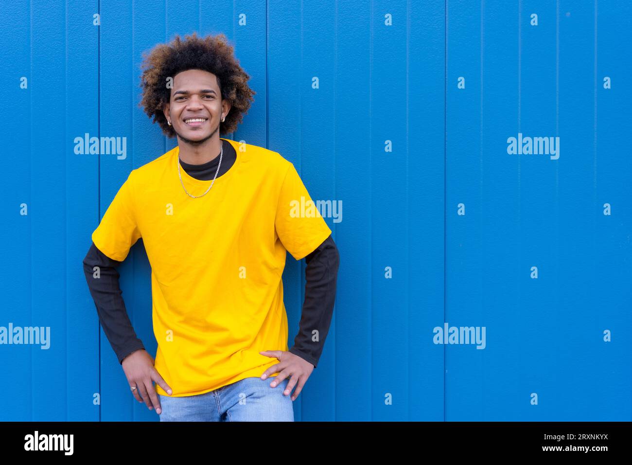 Horizontal photo with blue background of a cool african american young man standing and smiling Stock Photo