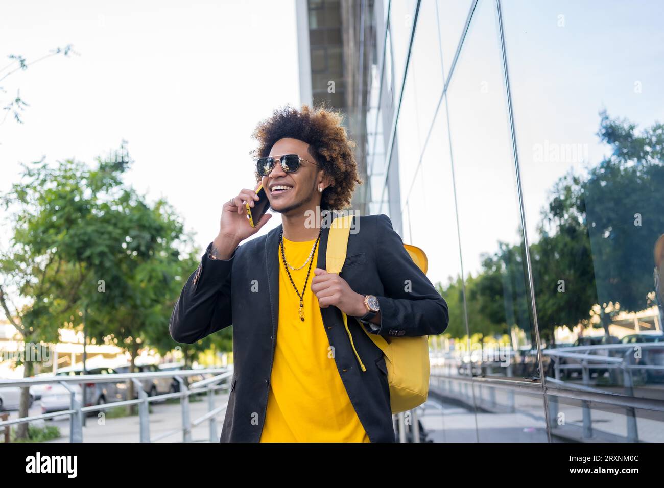 Casual stylish african american man talking to the phone while commuting with a bag Stock Photo