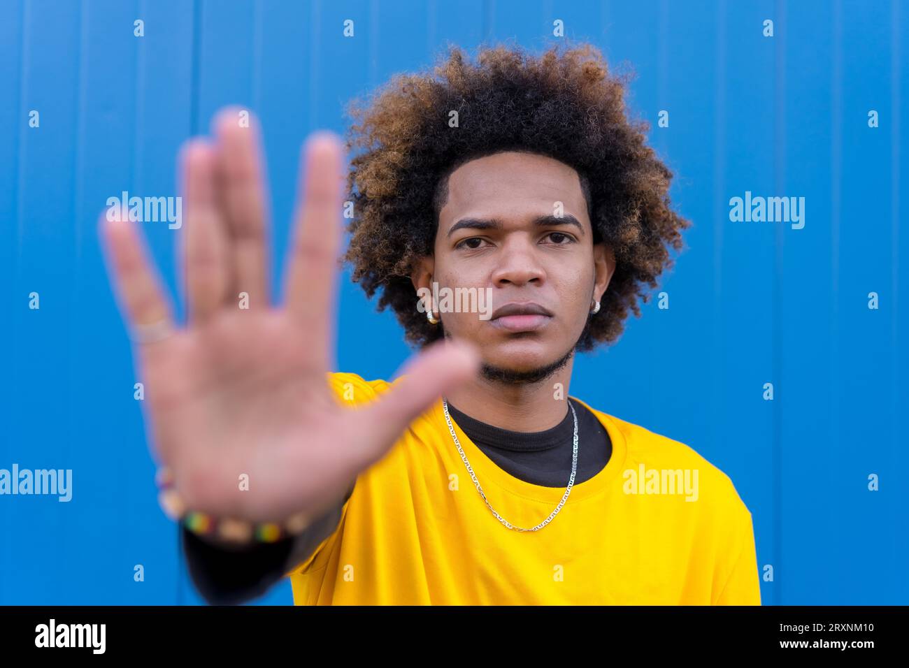 Horizontal photo with blue background of an african american young man gesturing stop with hand Stock Photo