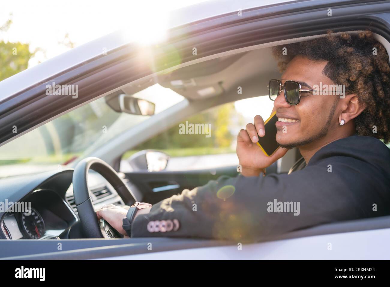 Side view photo of an african american elegant businessman talking to the mobile sitting inside a car Stock Photo