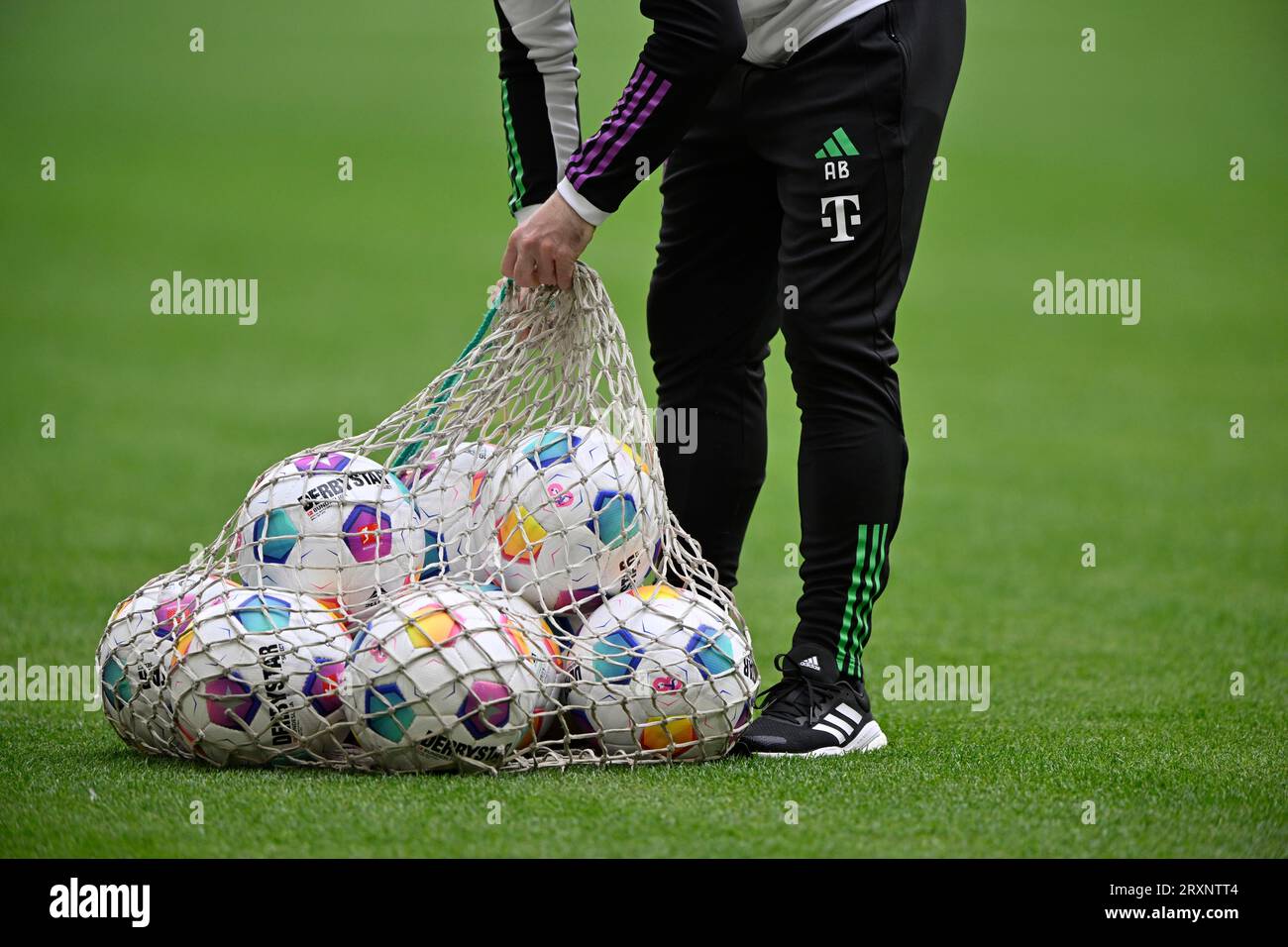 Assistant takes Adidas match balls Derbystar from ball net and puts them on the pitch for training and warm-up, Allianz Arena, Munich, Bavaria Stock Photo