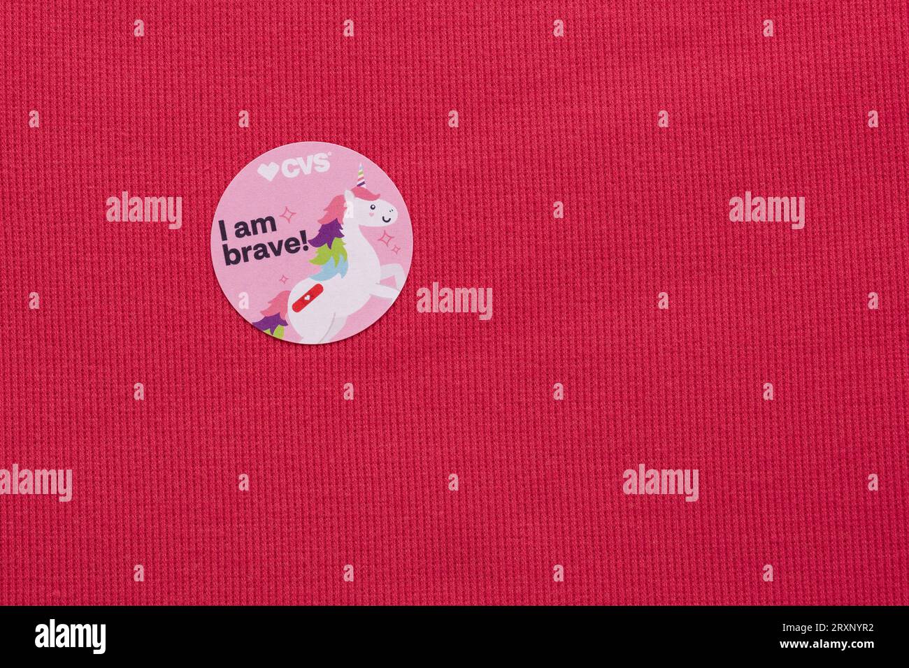 CVS childrens vaccine sticker on a pink t-shirt with unicorn and bandage and the saying "I am Brave!) Stock Photo