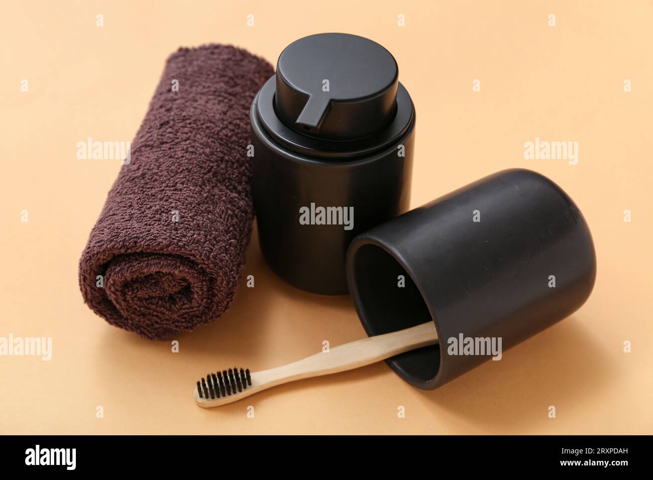 Holder with toothbrush, towel and bottle of cosmetic product on color background Stock Photo