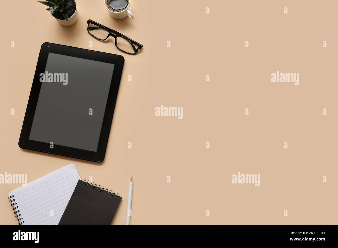 Tablet, notebooks and stationery on beige background Stock Photo