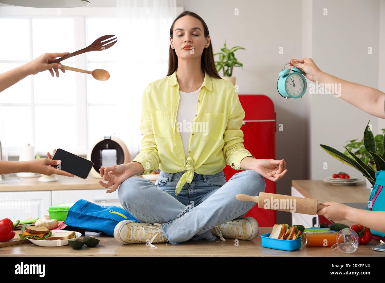 Young woman with a lot of things to do meditating in kitchen Stock Photo