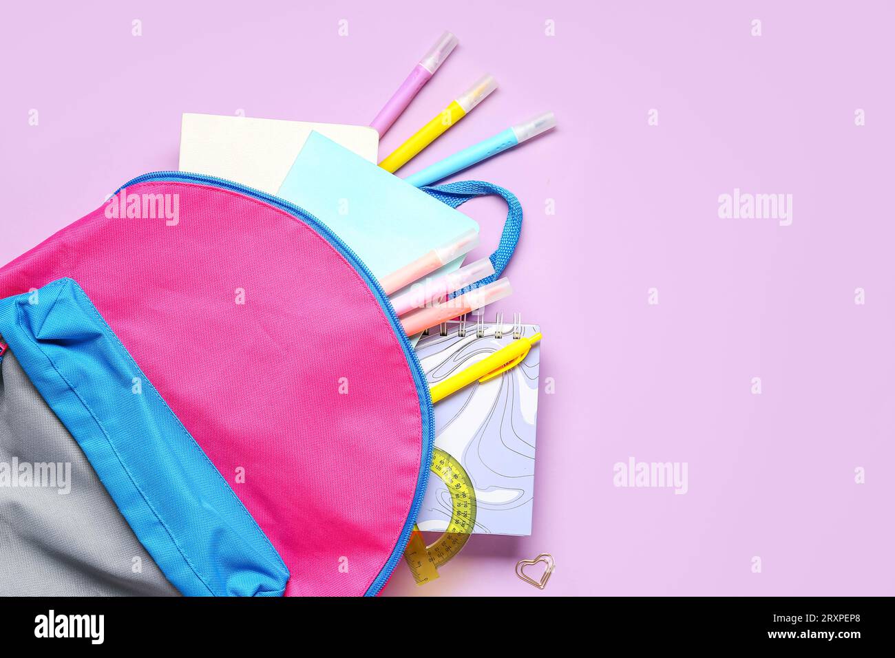 Stylish school backpack with different stationery on lilac background Stock Photo