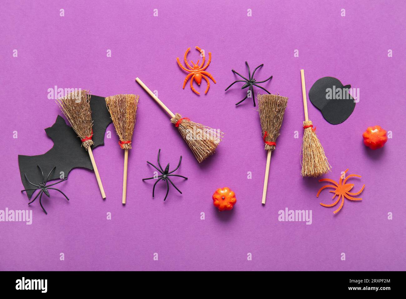 Halloween composition with brooms, spiders and pumpkins on purple ...