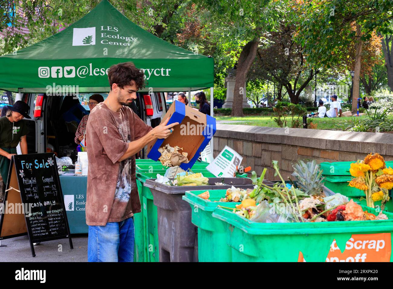 A person drops off food scraps and paper at the LES Ecology Center compost drop off booth in the Union Square Greenmarket, New York City. Stock Photo