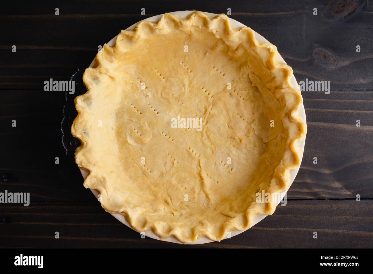 Unbaked Pie Crust Dough with Pinched Edges in a Pie Pan: Raw pie crust dough with crimped edges in a deep ceramic pie dish Stock Photo