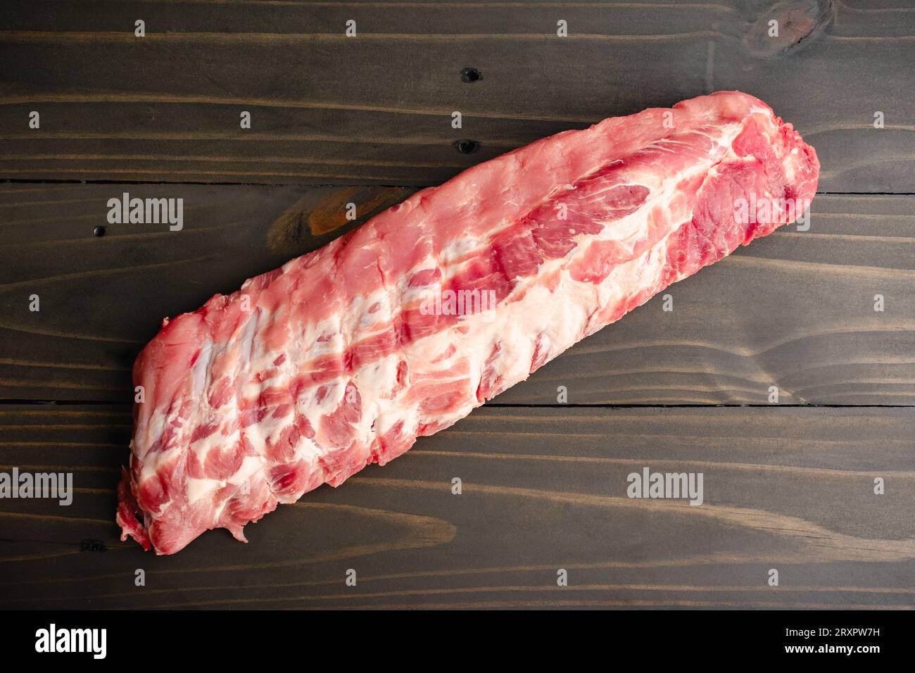 Raw Rack of Baby Back Ribs on a Wooden Table An uncooked rack of pork