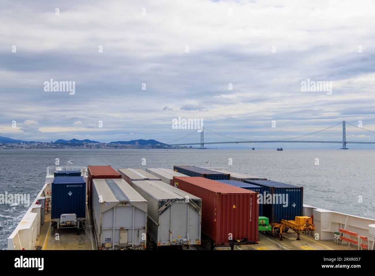 Kobe, Japan September 23, 2023 Shipping containers on ferry sail by Akashi suspension bridge