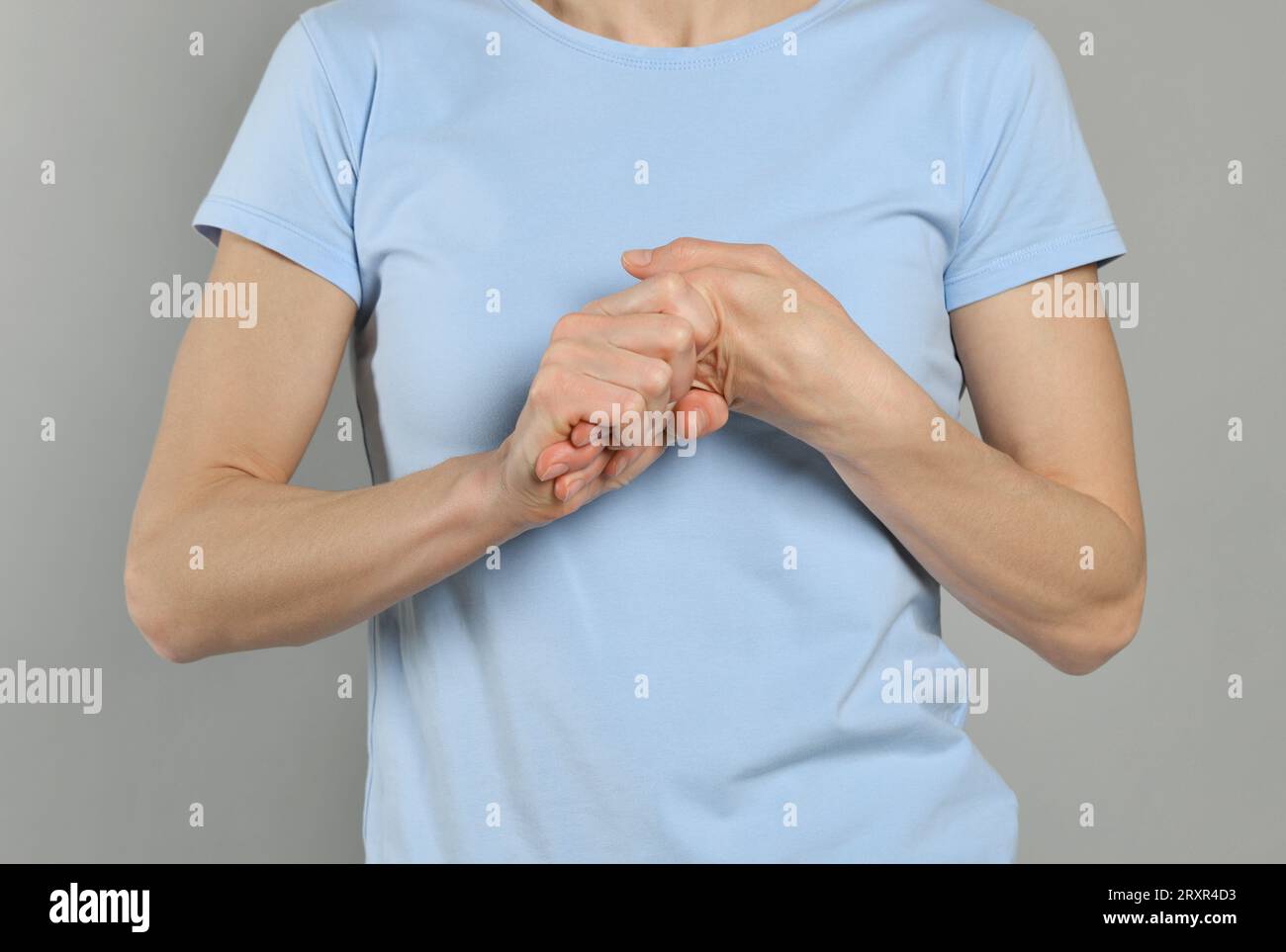 Woman cracking her knuckles on light grey background, closeup. Bad