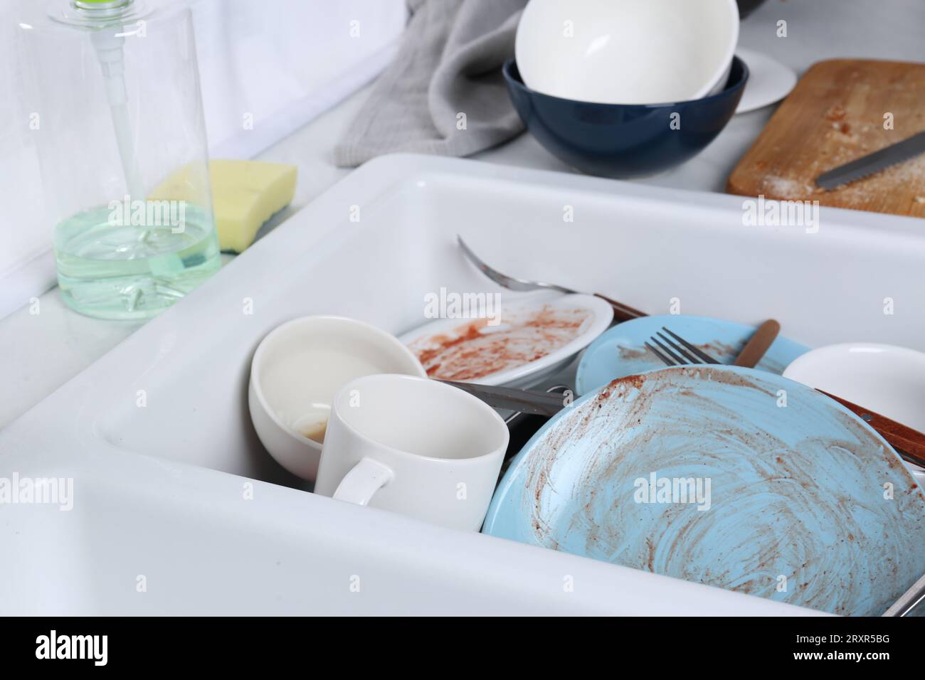 Sink with many dirty utensils and dishware in messy kitchen Stock Photo