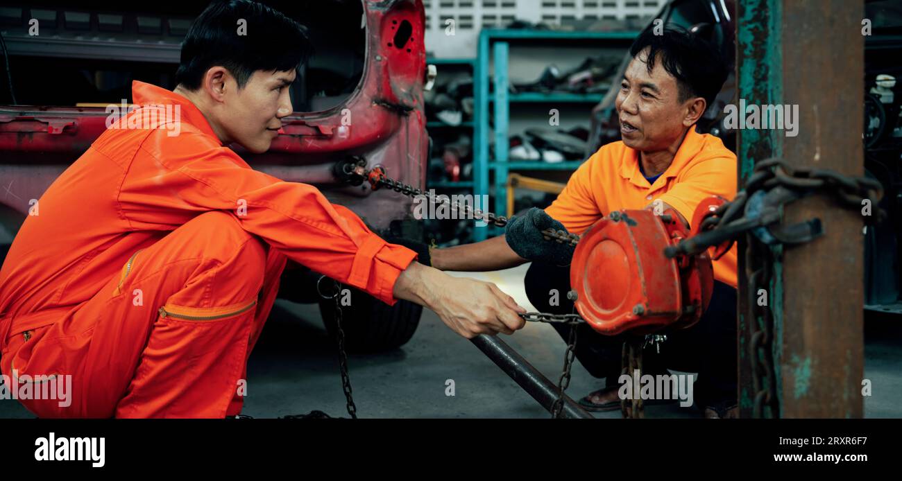 Mechanic testing strength and reliability of chain hoist for car towing