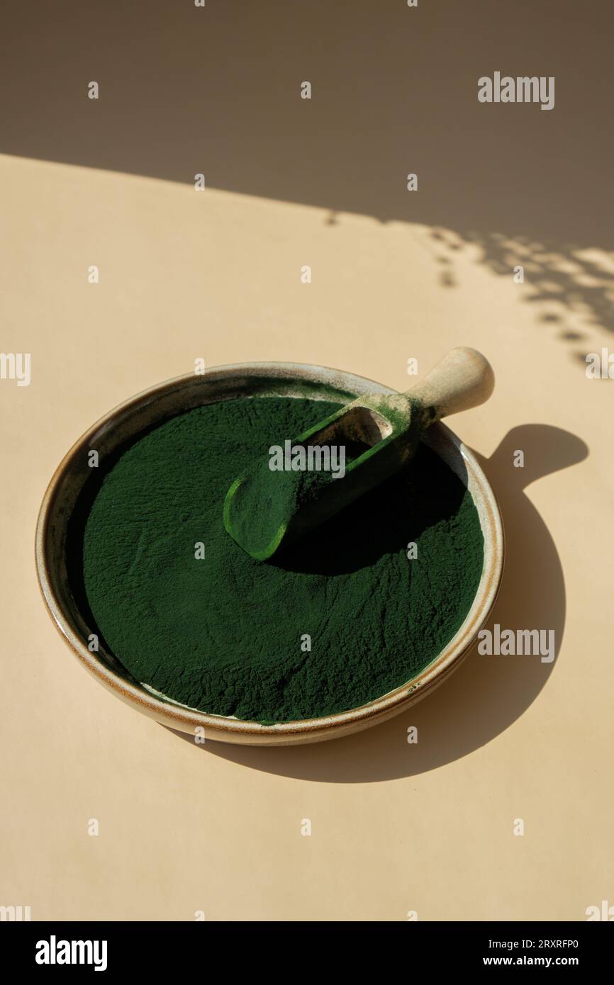 Organic blue-green algae spirulina powder food in plate with wooden ...