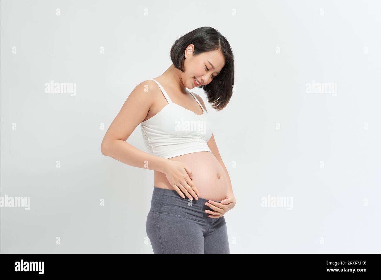 pregnant woman holding her belly on wite background Stock Photo - Alamy
