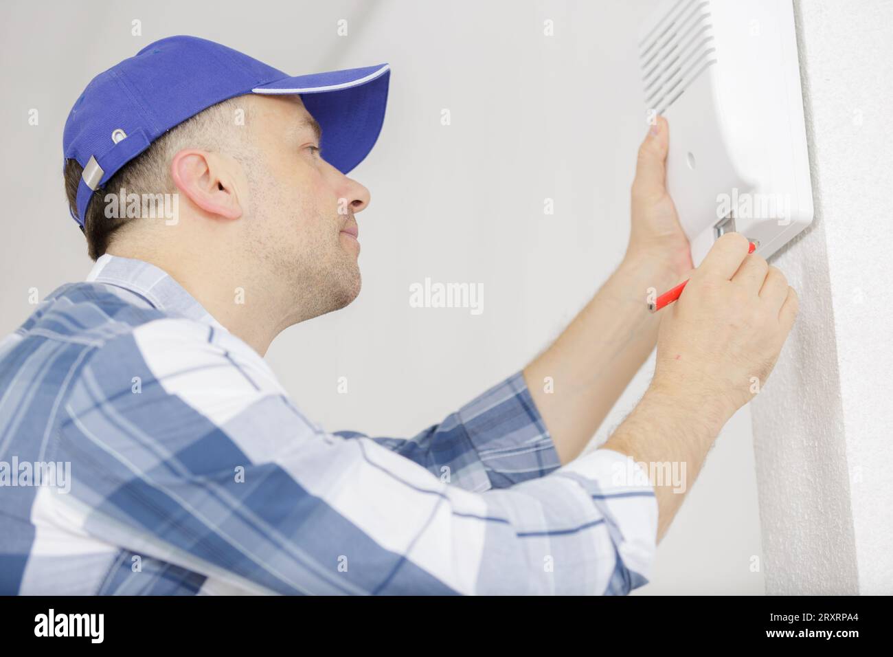 male technician installing alarm system indoors Stock Photo