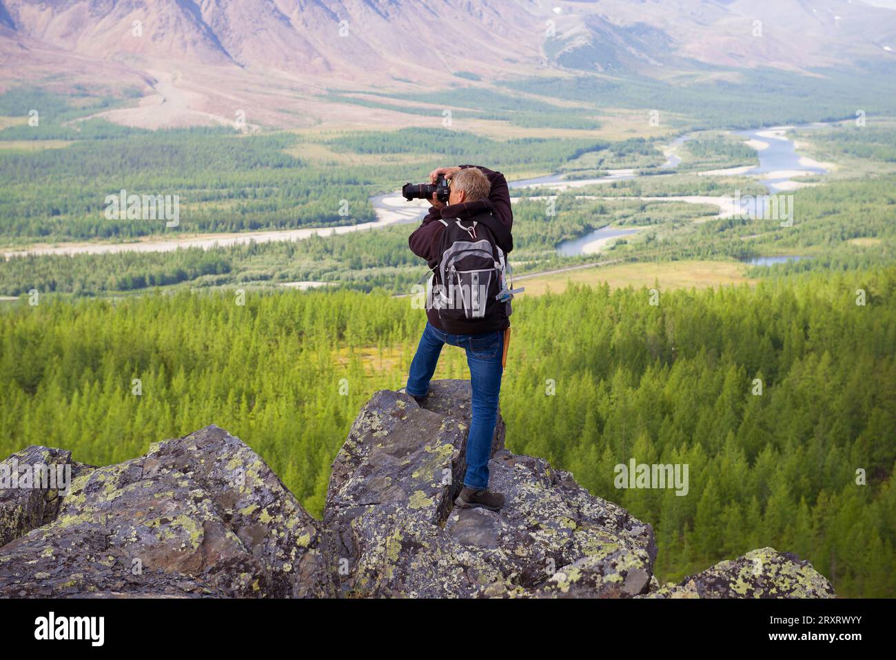 YAMAL, RUSSIA - AUGUST 20, 2018: A photographer in the mountains of the Polar Urals photographs the Sob River valley Stock Photo