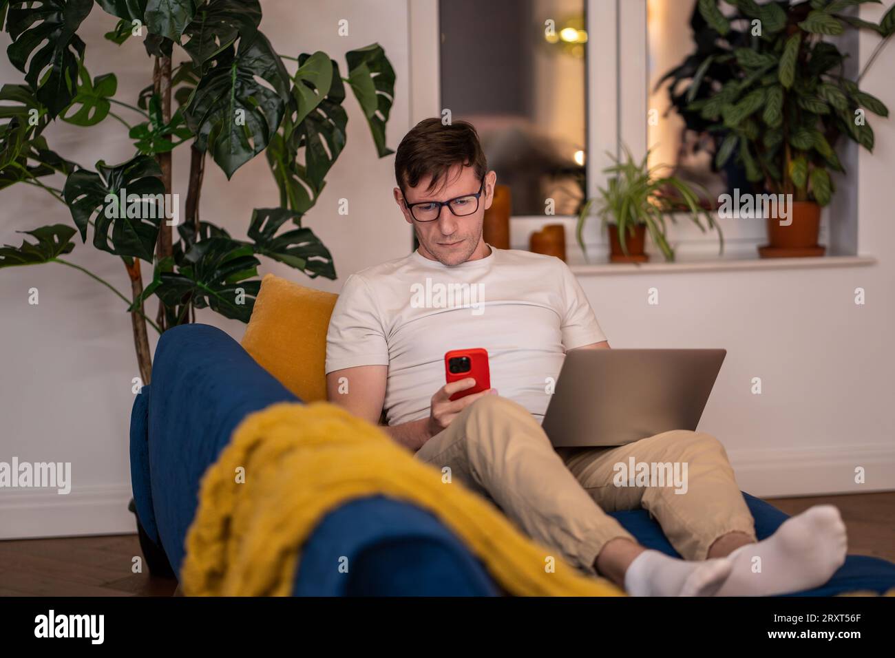 Man IT specialist working on laptop smartphone testing new programming apps Stock Photo
