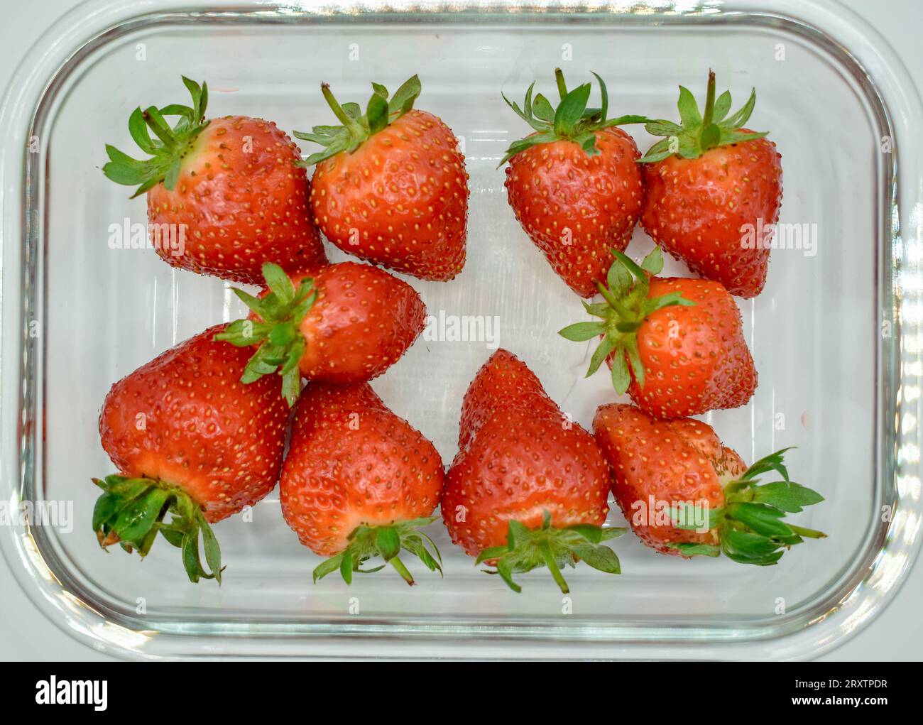 A clear glass dish containing some juicy red strawberries photographed against a white background. Stock Photo