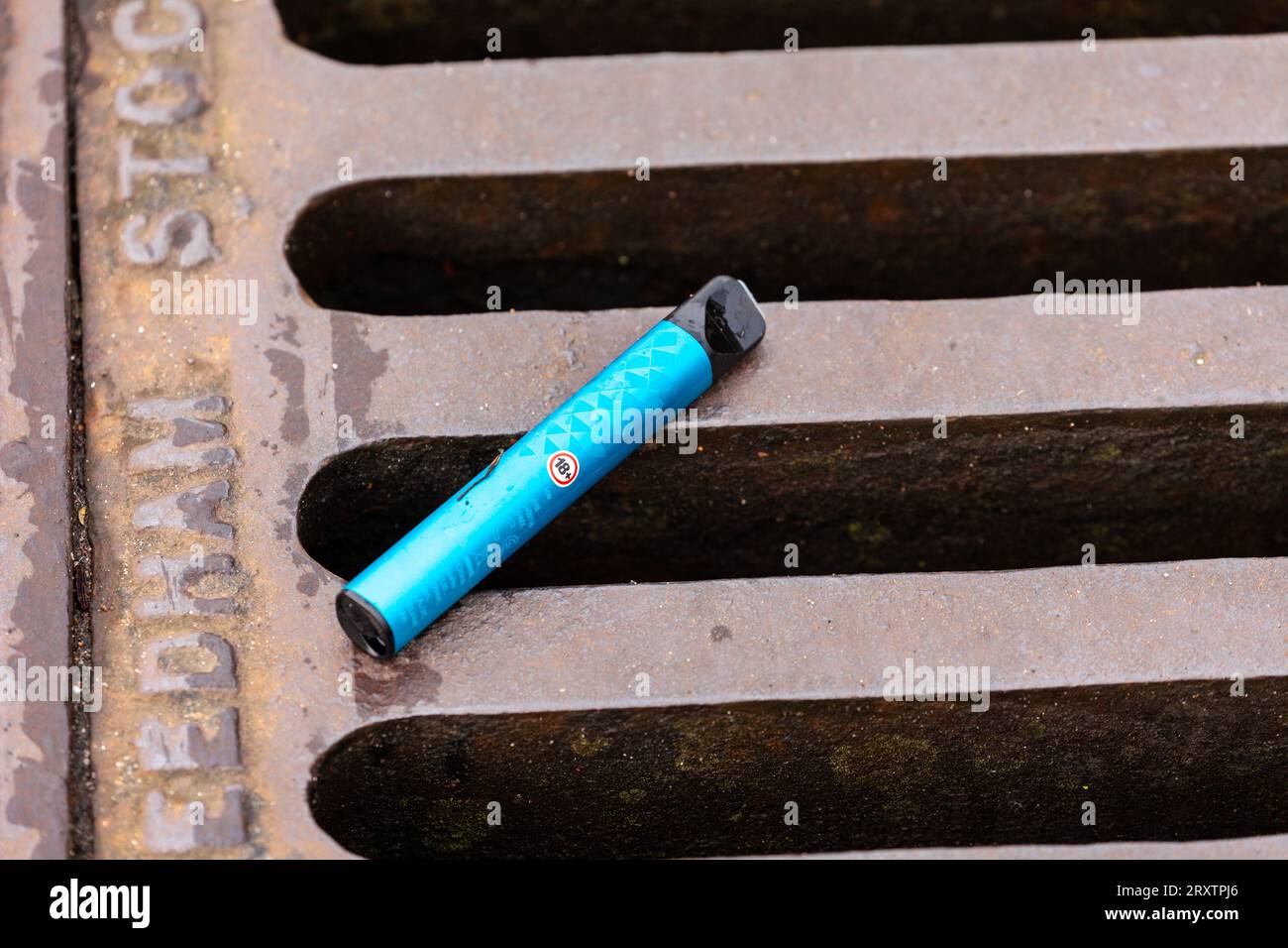 Single use disposable vape lying on a road drain Stock Photo